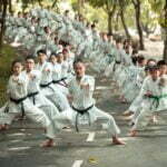 people in white uniform sitting on gray concrete road during daytime