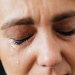 Tears on face of crop anonymous woman